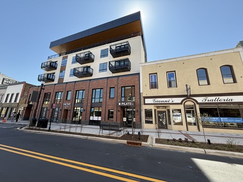 A sunny day in a city street with a building that has a sign that says "Gianni's Pizzeria".