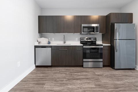 A modern kitchen with dark wood cabinets and stainless steel appliances.