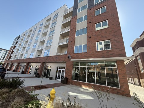 A tall building with a red brick facade and a yellow fire hydrant in front.