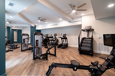 A gym with a variety of exercise equipment including treadmills, stationary bikes, and weight machines.