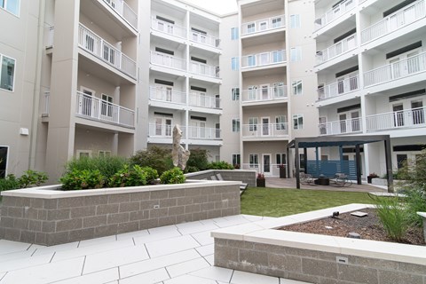 A large white building with balconies and a small garden in front.