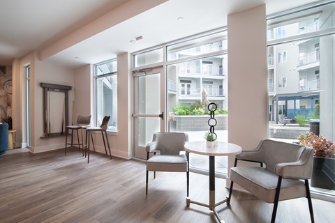 A room with a table and chairs with a view of a building outside the window.
