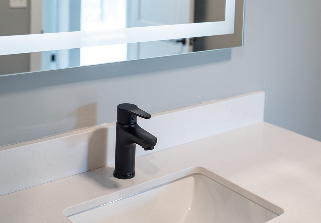 a bathroom sink with a black faucet and a mirror