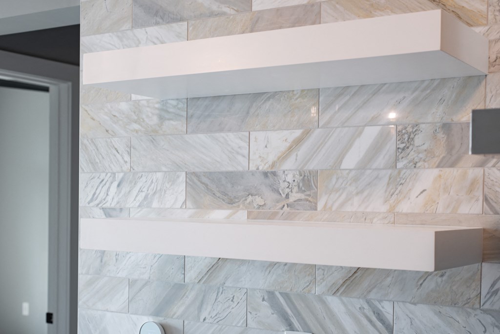 a close up of a marble wall with shelves in a bathroom