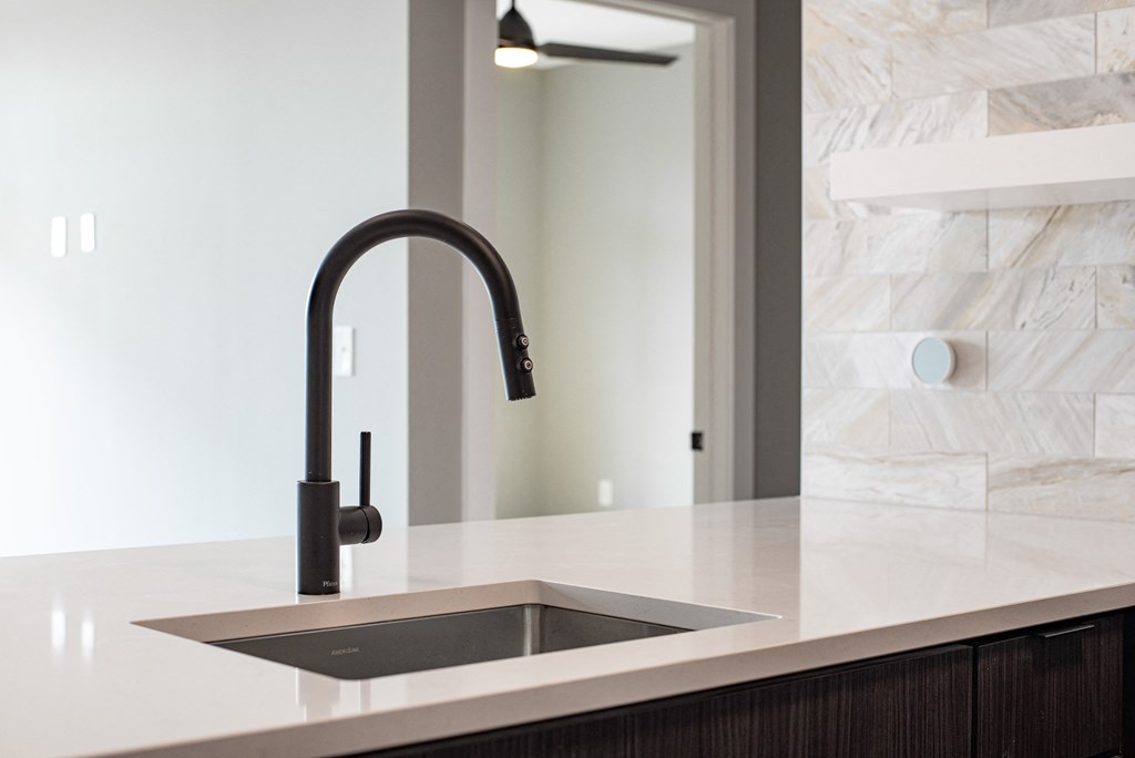 a kitchen counter with a sink and a black faucet