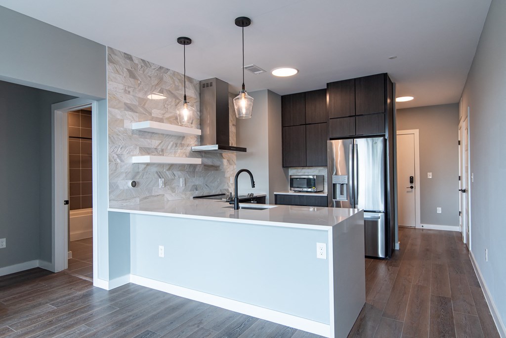 a kitchen with a large island and a stainless steel refrigerator