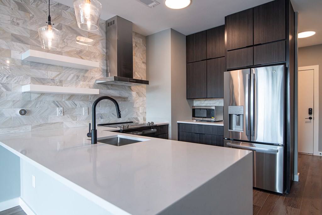 a kitchen with a large island and a stainless steel refrigerator