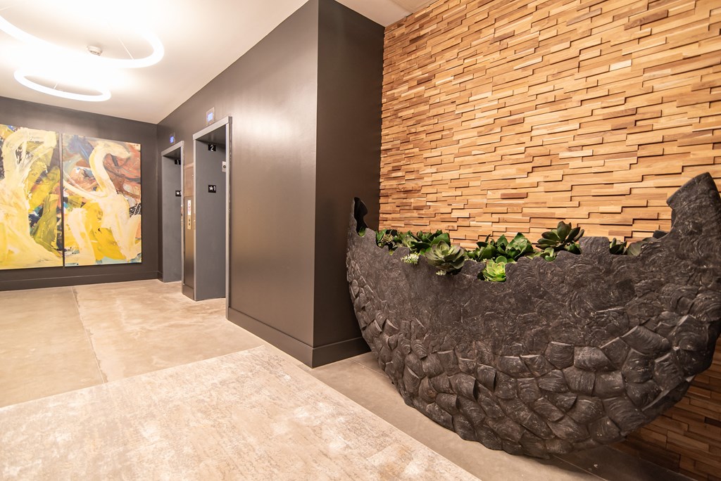 a rock wall in a hallway with a door and a painting