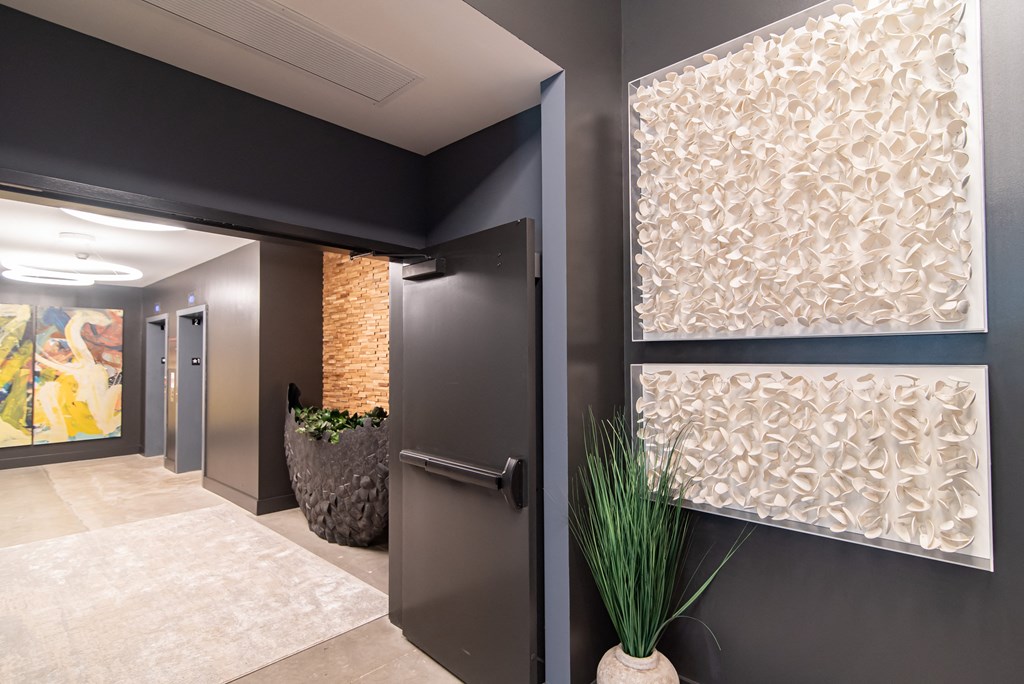 a hallway with a black door and a potted plant