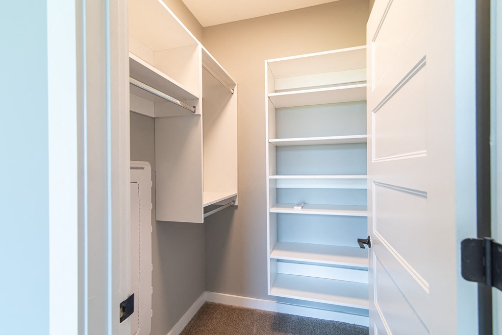 a walk in closet with shelves and a white door