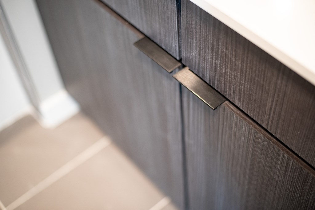 A close up of a drawer handle on a wooden cabinet.