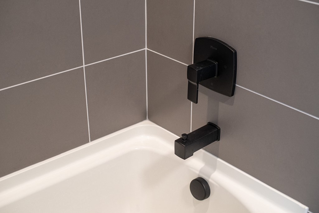 a white bath tub with a black faucet in a bathroom