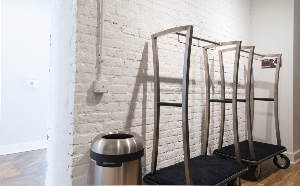 a white brick wall with metaladders and a trash can