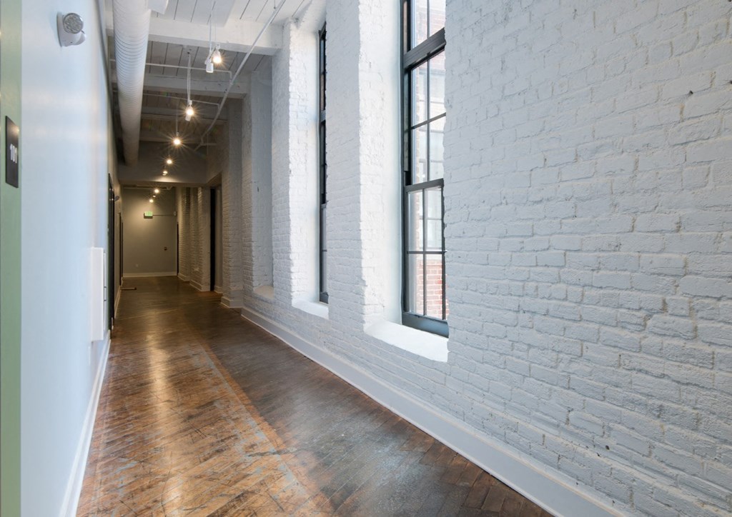 a long hallway with white brick walls and large windows