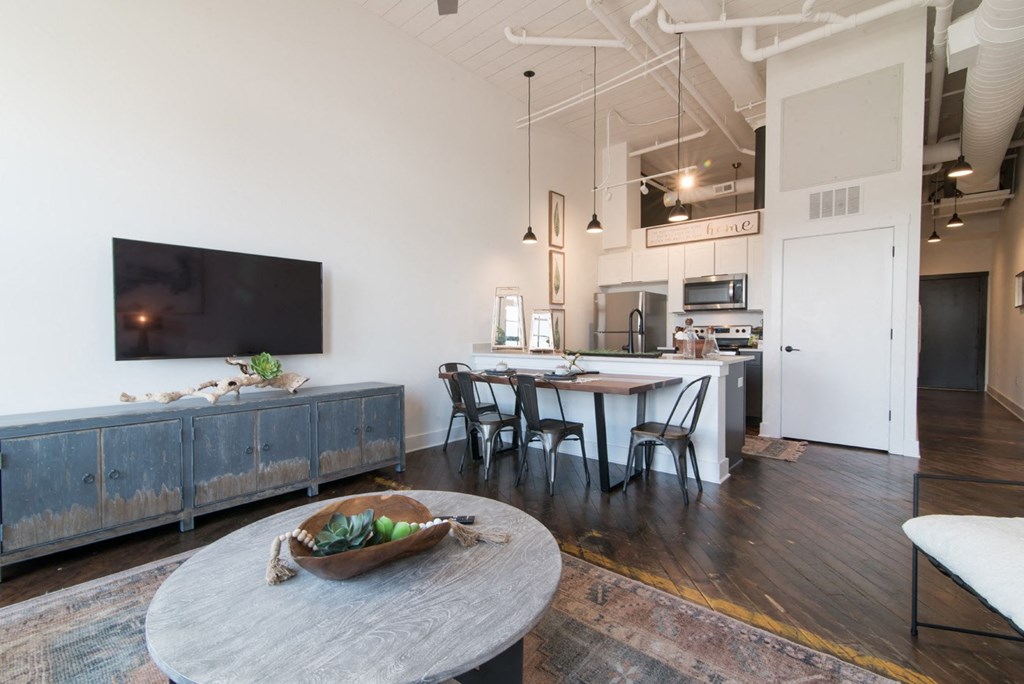 a living room and kitchen with a dining table and a television
