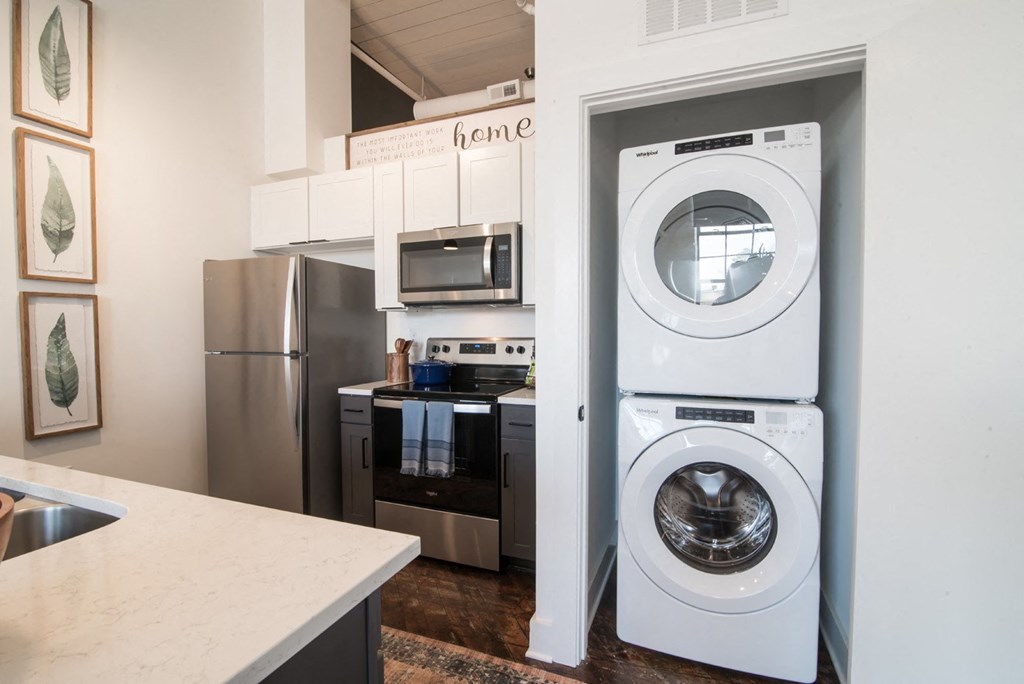 a washer and dryer in a kitchen with a stainless steel refrigerator