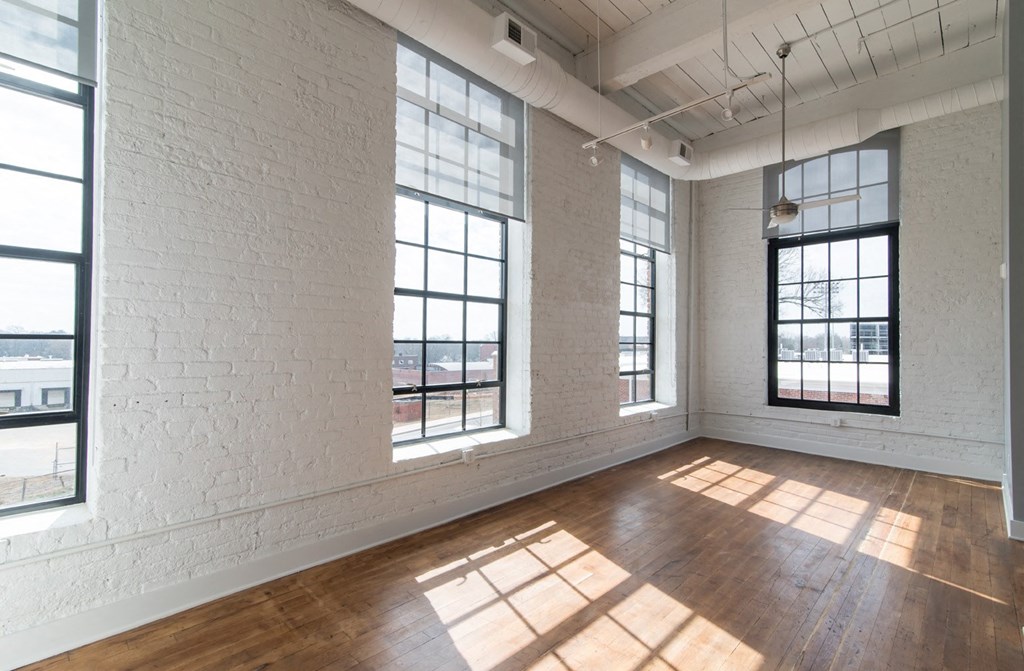 an empty living room with large windows and wood floors