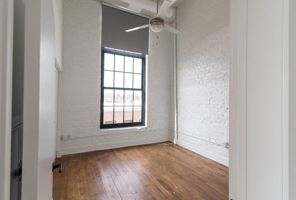 an empty room with a window and wood floors