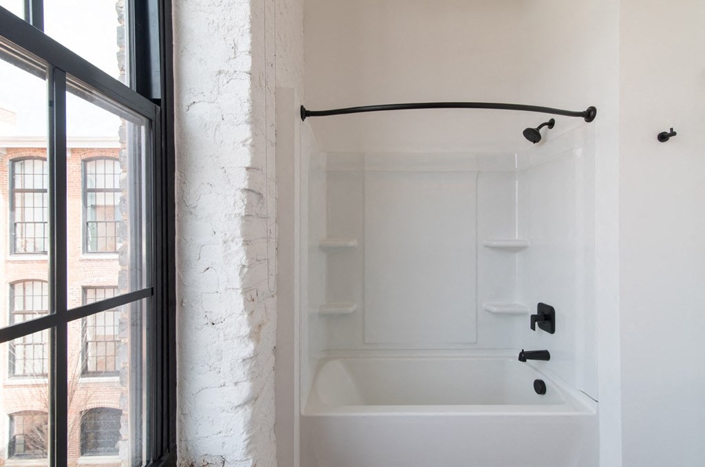 a white bathroom with a tub and a window