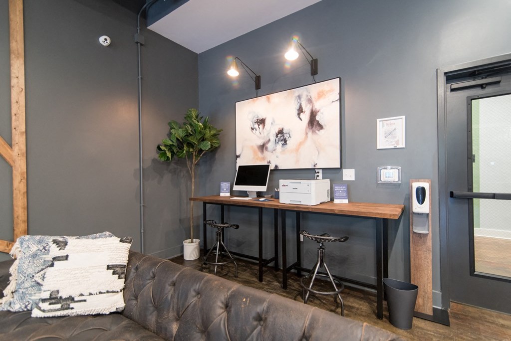 a home office with a computer and a painting on the wall