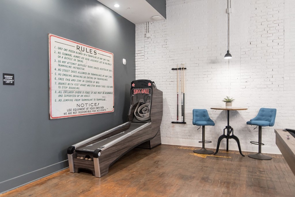 a game room with a white brick wall and a pinball machine