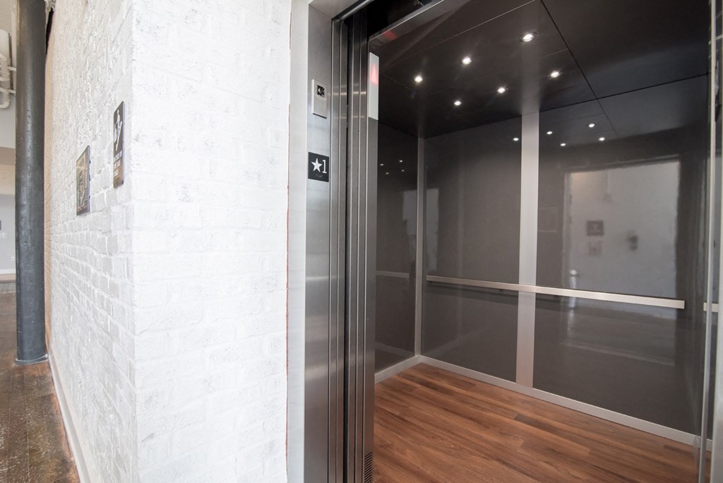 a glass elevator in a lobby with a wood floor