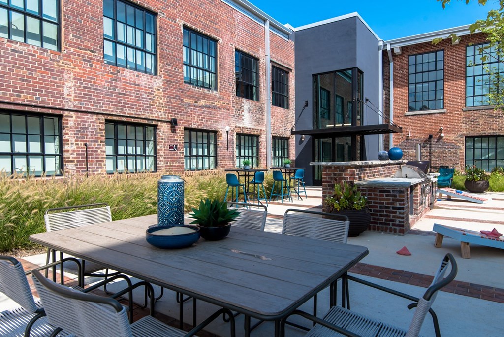 a patio with a table and chairs in front of a brick building