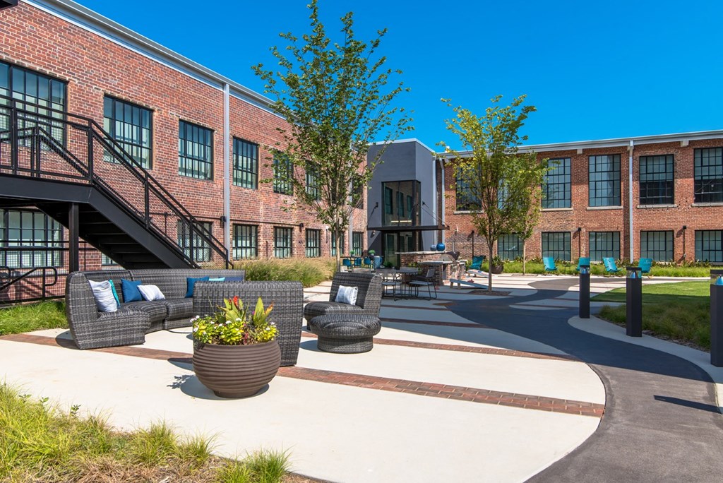 a courtyard with couches and tables in front of a brick building