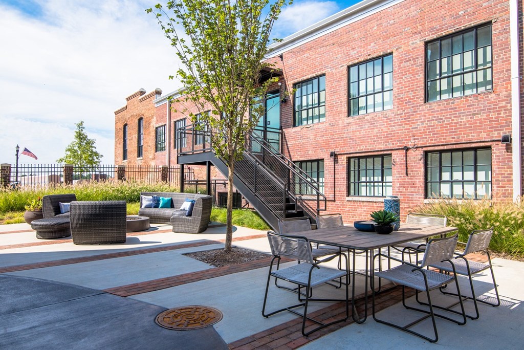 a patio with a table and chairs in front of a brick building