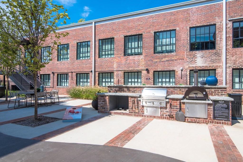 a brick building with a barbecue grill and a tree in front of it