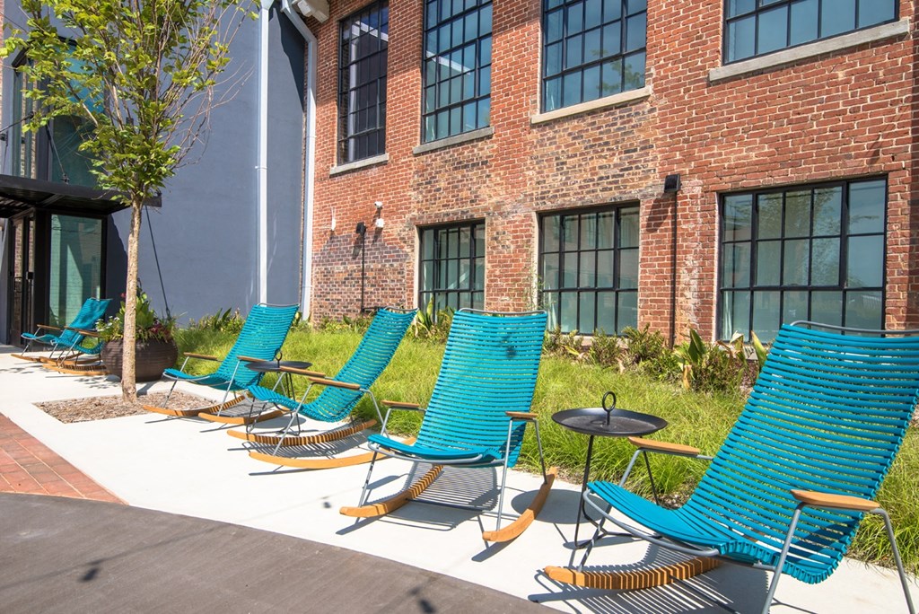 a row of blue lounge chairs in front of a brick building