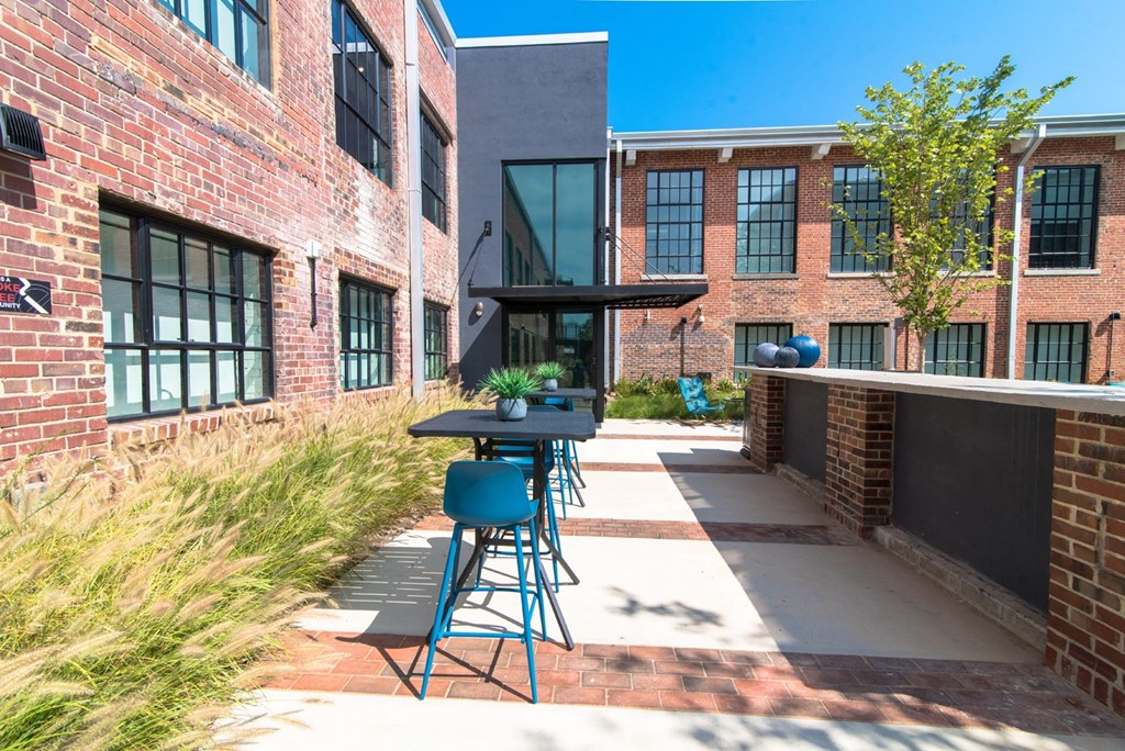 a patio with chairs and tables in front of a brick building
