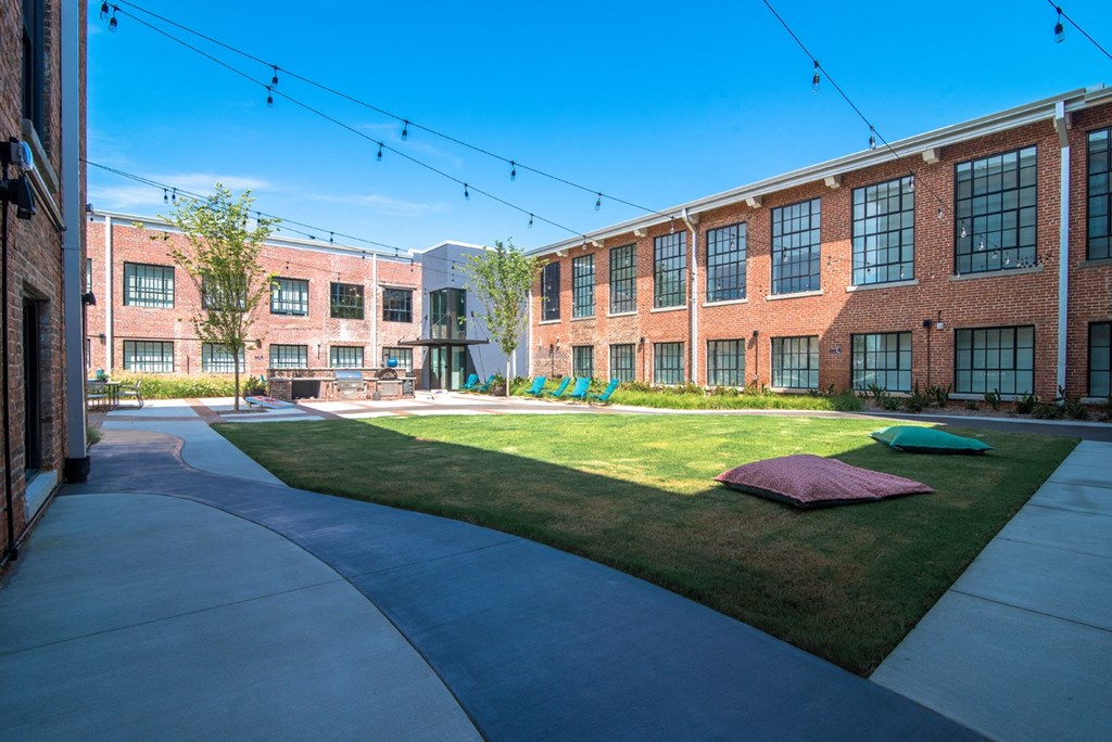 a large brick building with grass and a sidewalk in front of it