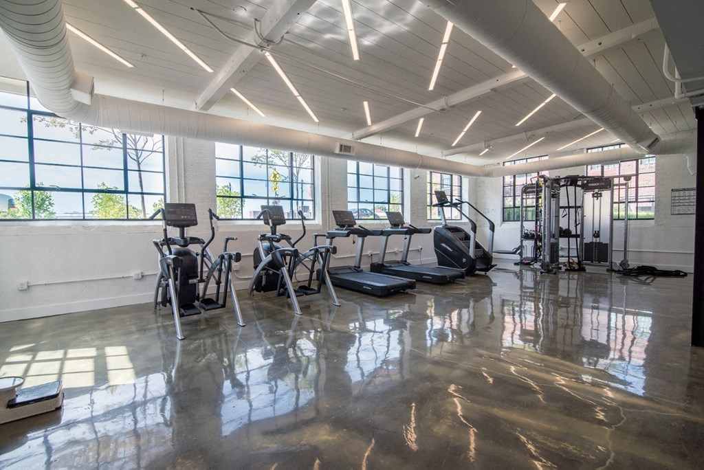 a workout room with cardio equipment and windows in a building