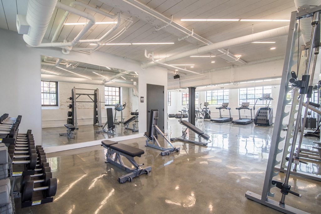 a gym with weights and cardio equipment in a building with windows