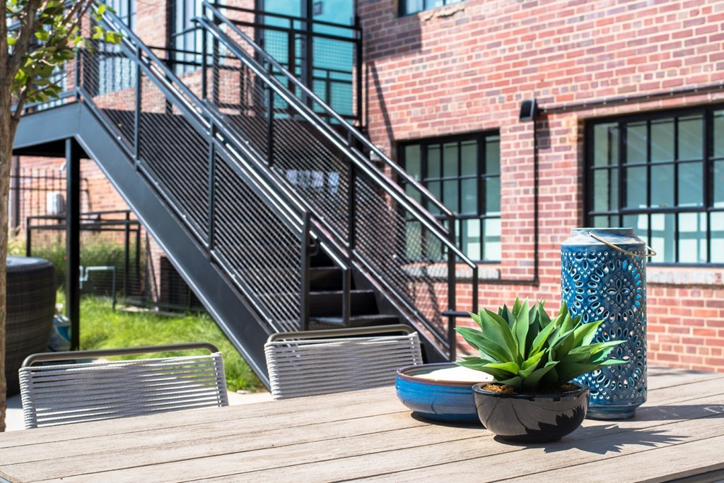 a wooden deck in front of a brick building with stairs