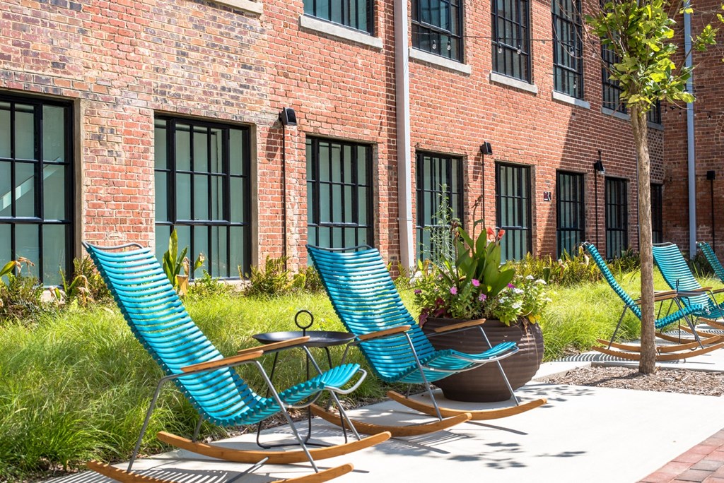 a row of blue lounge chairs in front of a brick building