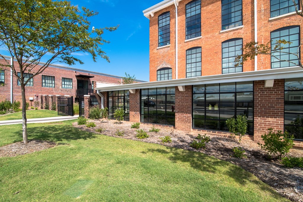 the front of a brick building with grass and trees