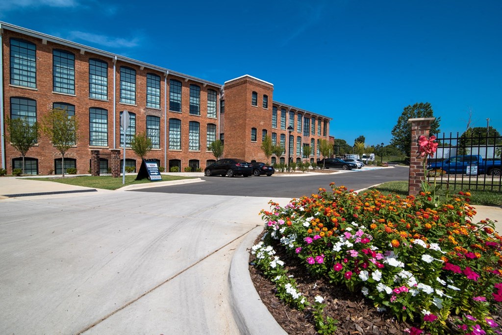 a large brick building with a flower garden in front of it