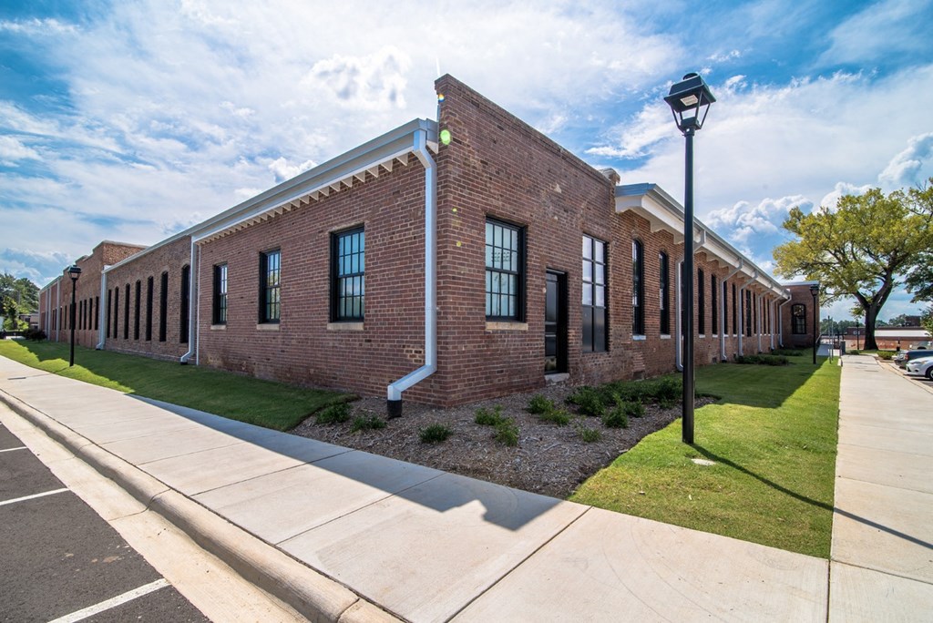 the exterior of a brick building with a sidewalk and grass