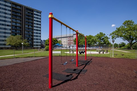 a swing set in a park with a building in the background