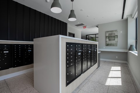 A modern mail room lobby with a reception desk and a view of the outside at The Rail at Bound Brook, NJ.