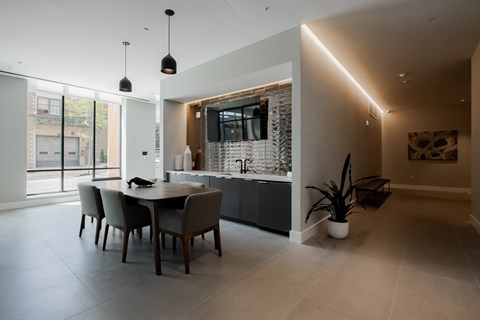 Modern resident lounge in The Rail at Bound Brook with open floorplan, stylish chairs, large TV, and community dining space.