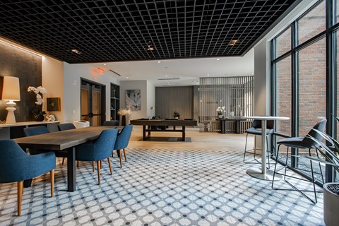 Resident clubroom at The Rail at Bound Brook featuring a pool table, large dining table, and natural light in Bound Brook, NJ.