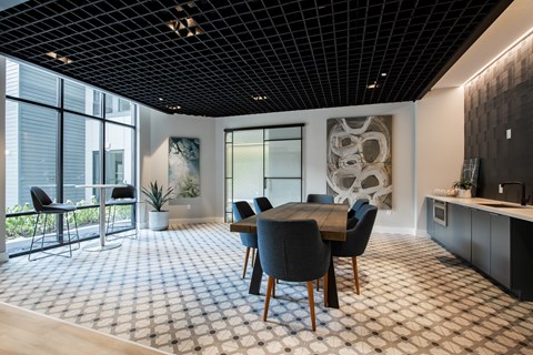 Resident lounge at The Rail featuring a large wooden dining table, designer lighting, and floor-to-ceiling windows.