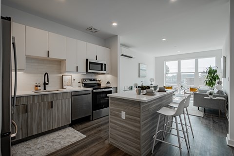 Designer kitchen with quartz countertops, bar seating, and two-tone cabinetry—part of the modern luxury amenities at The Rail Bound Brook.