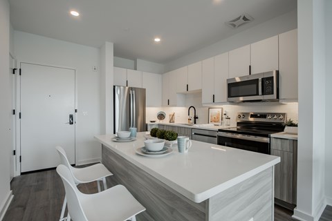 Luxury apartment kitchen and living area at The Rail at Bound Brook, NJ—featuring modern apartment amenities, quartz countertops, and stainless steel appliances in a spacious open-concept layout.