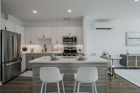 Contemporary kitchen at The Rail featuring white cabinetry, subway tile backsplash, stainless steel appliances, and natural light from large windows.