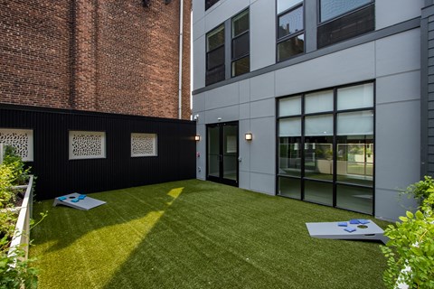 Outdoor courtyard space at The Rail at Bound Brook featuring cornhole and turf—part of the community’s luxury apartment amenities in Bound Brook, NJ.