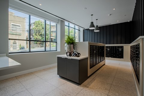 A modern mail room lobby with a reception desk and a view of the outside at The Rail at Bound Brook, NJ.